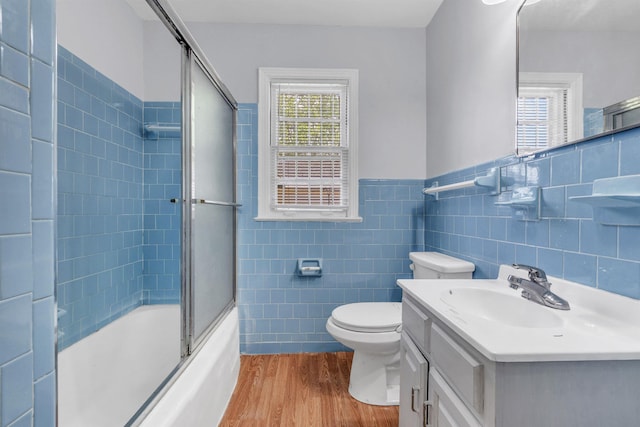 686 Looney Ave, Memphis, TN 38107 - bathroom featuring wood finished floors, tile walls, toilet, shower / bath combination with glass door, and vanity