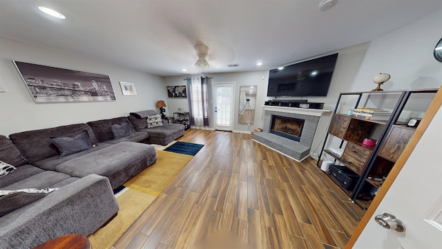 living area featuring ceiling fan, wood finished floors, a brick fireplace, and recessed lighting