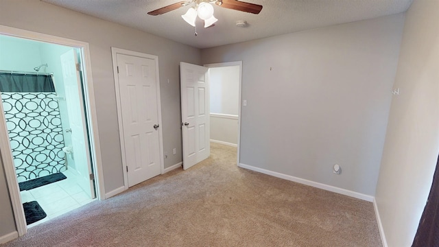 unfurnished bedroom featuring carpet, baseboards, ensuite bath, a textured ceiling, and a ceiling fan