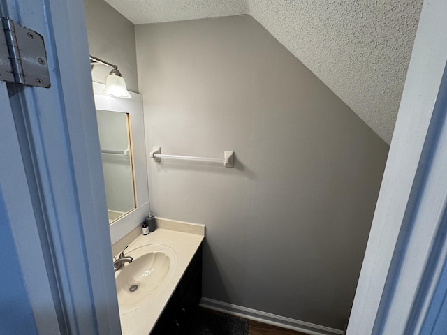 bathroom featuring a textured ceiling, lofted ceiling, and vanity