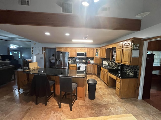 8130 Julie Cv, Millington, TN 38053 - kitchen featuring appliances with stainless steel finishes, a breakfast bar area, dark countertops, decorative backsplash, and recessed lighting