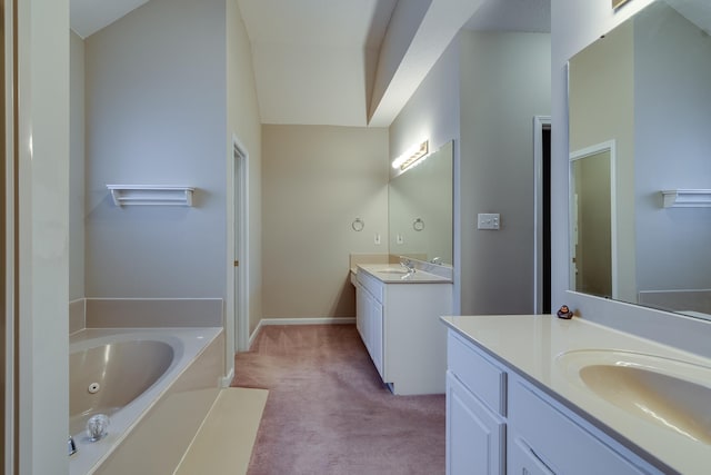 full bathroom with two vanities, a jetted tub, and baseboards