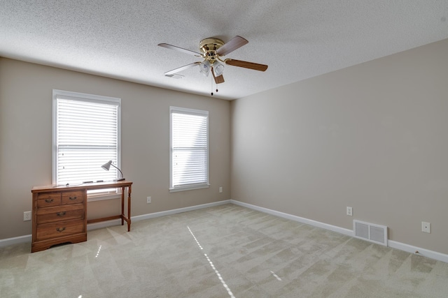 unfurnished bedroom featuring light carpet, a textured ceiling, baseboards, and ceiling fan