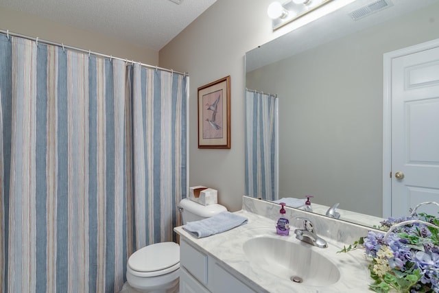 full bath featuring toilet, vanity, and a textured ceiling