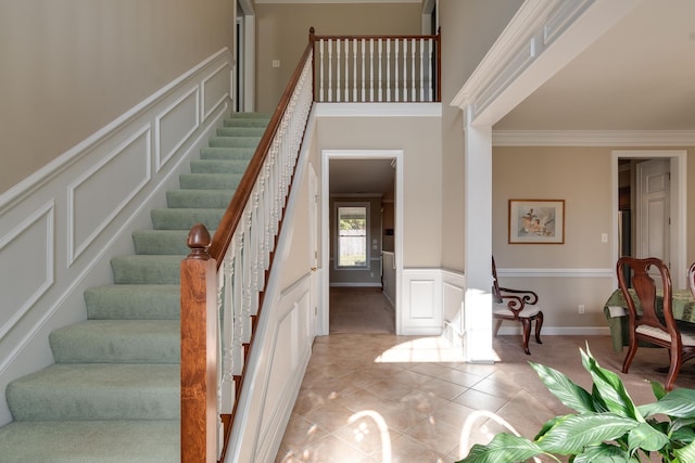 entryway featuring a decorative wall, a wainscoted wall, stairs, and ornamental molding
