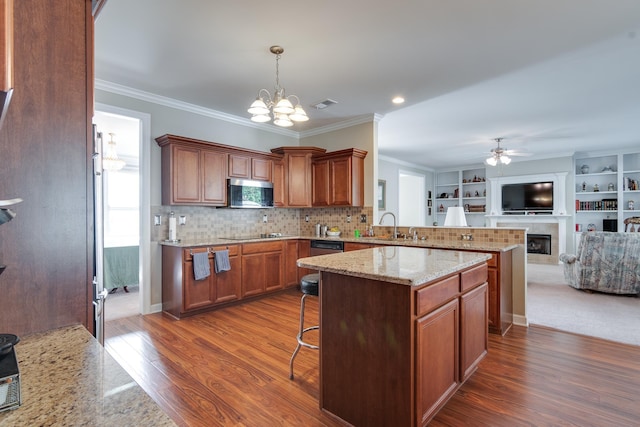 kitchen with stainless steel microwave, open floor plan, a tiled fireplace, a chandelier, and a breakfast bar