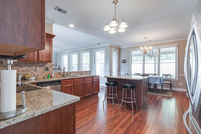kitchen with a chandelier, a sink, appliances with stainless steel finishes, dark wood-style floors, and crown molding