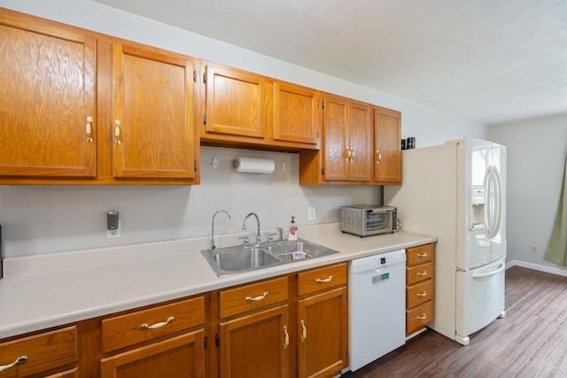kitchen featuring white appliances, a sink, light countertops, dark wood-style floors, and brown cabinets