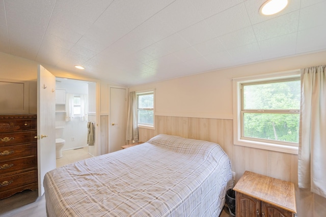 bedroom with wainscoting and connected bathroom