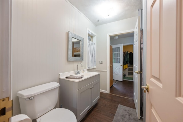 bathroom with wood finished floors, toilet, and vanity