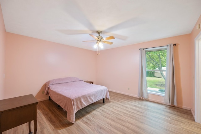 bedroom featuring light wood finished floors, baseboards, and ceiling fan