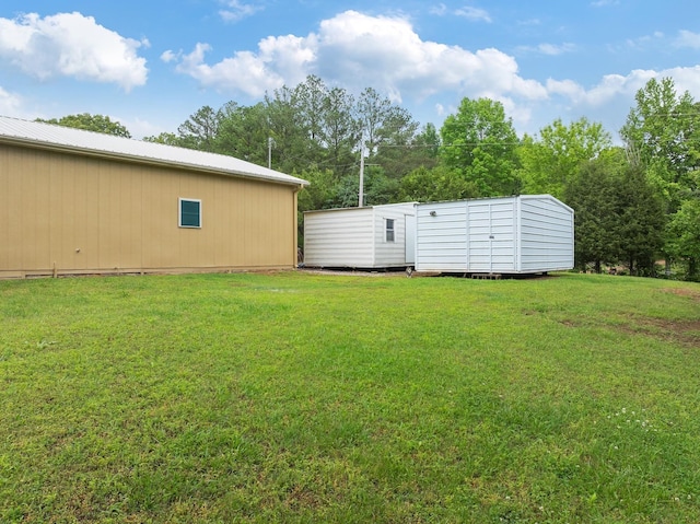 view of green lawn with an outbuilding and a storage unit