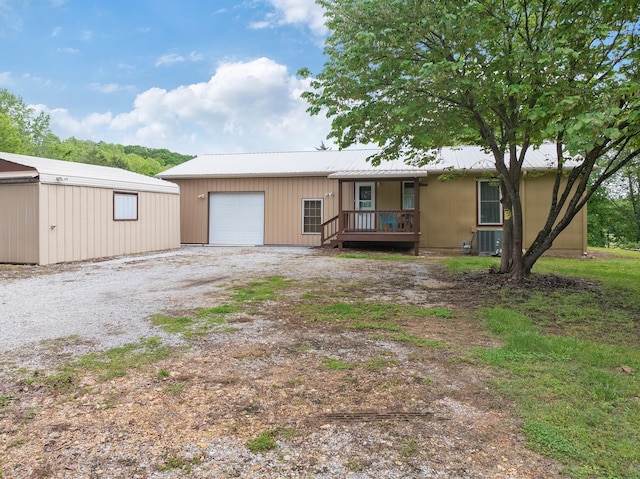view of front of property with driveway, a garage, metal roof, and a porch