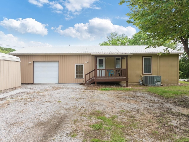 view of front facade featuring a porch, central AC unit, metal roof, and driveway