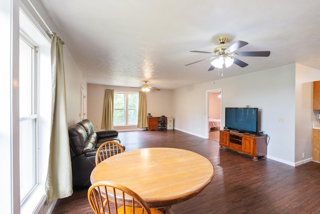 dining room with dark wood finished floors, a ceiling fan, and baseboards