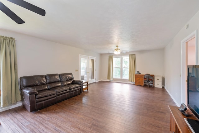 living area featuring ceiling fan, wood finished floors, a desk, and baseboards