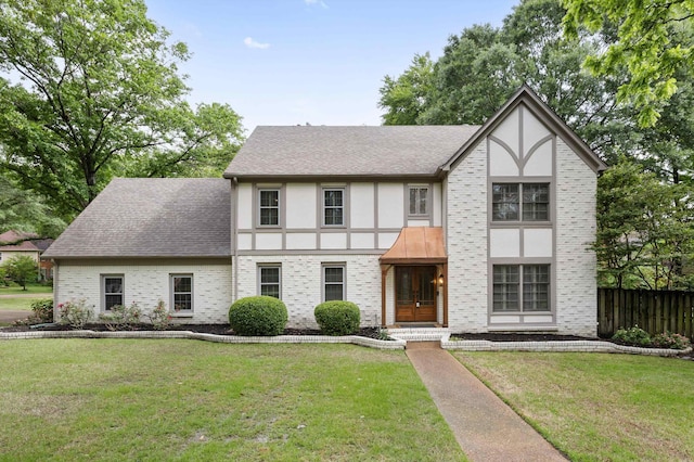 tudor home with stucco siding, brick siding, and a shingled roof