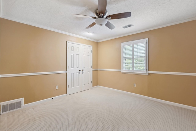 carpeted spare room featuring a ceiling fan, ornamental molding, baseboards, and a textured ceiling