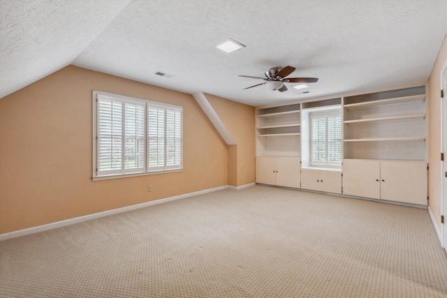 bonus room featuring light colored carpet, baseboards, ceiling fan, lofted ceiling, and plenty of natural light