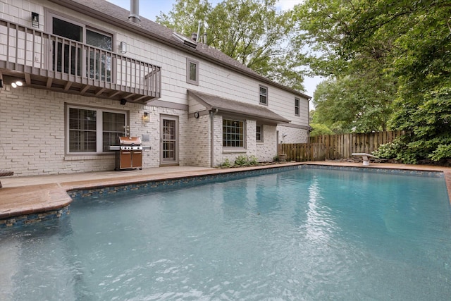 view of swimming pool featuring a fenced backyard, grilling area, and a diving board