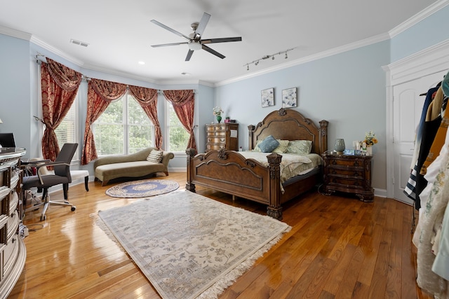 bedroom featuring track lighting, crown molding, wood finished floors, ceiling fan, and baseboards