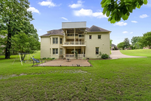 rear view of house with a patio area, a balcony, and a lawn