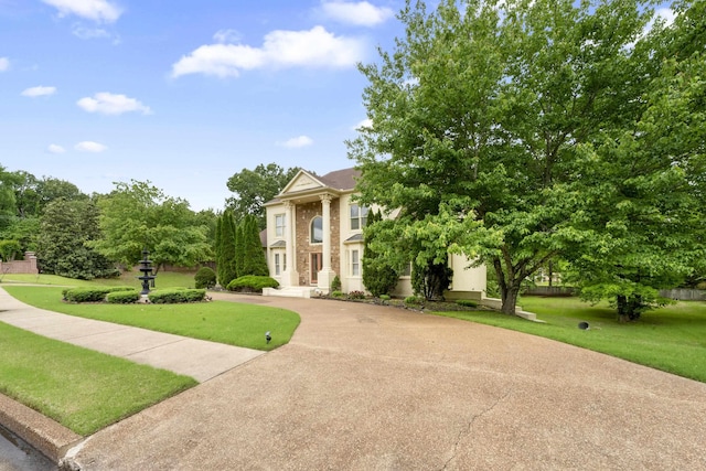 neoclassical home featuring a front lawn and curved driveway