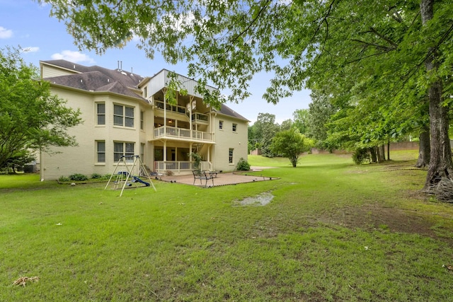 rear view of property featuring a balcony, a patio, a yard, and stucco siding