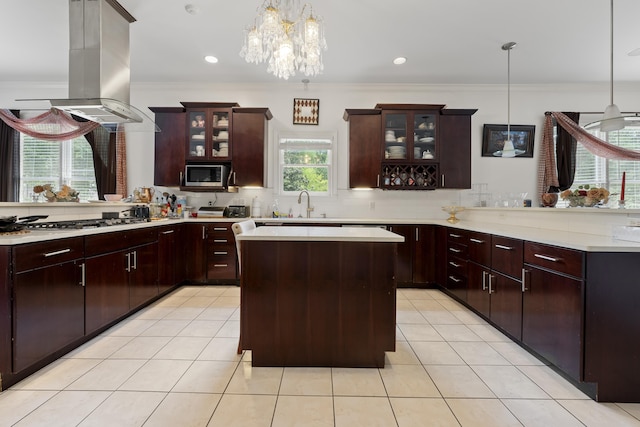 kitchen with stainless steel appliances, a peninsula, ornamental molding, light countertops, and island range hood
