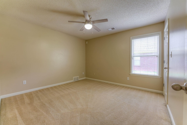 unfurnished room featuring a ceiling fan, a textured ceiling, light colored carpet, and baseboards