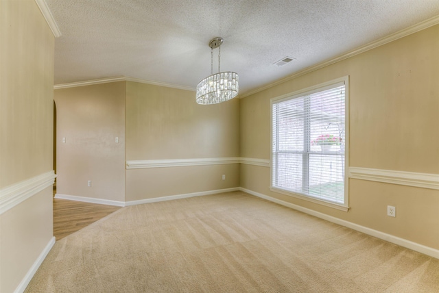 carpeted spare room featuring crown molding, a chandelier, a textured ceiling, and baseboards
