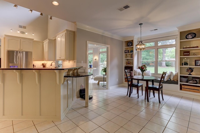 1917 Steeplebrook Cv, Cordova, TN 38016 - kitchen with stainless steel fridge, a breakfast bar, dark countertops, light tile patterned floors, and decorative light fixtures