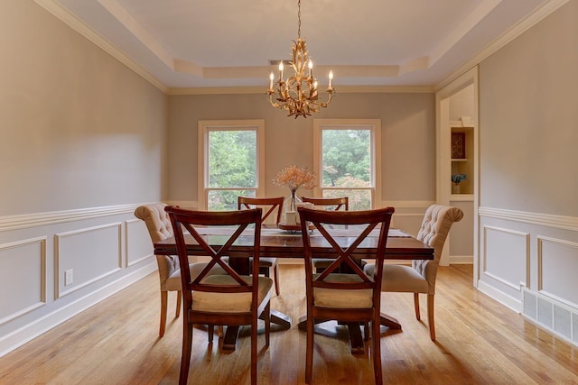 1917 Steeplebrook Cv, Cordova, TN 38016 - dining room featuring a chandelier, a raised ceiling, a decorative wall, light wood-style floors, and wainscoting