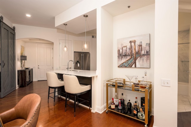 717 S Riverside Dr Unit 1203, Memphis, TN 38103 - bar with high quality fridge, a sink, arched walkways, dark wood finished floors, and pendant lighting