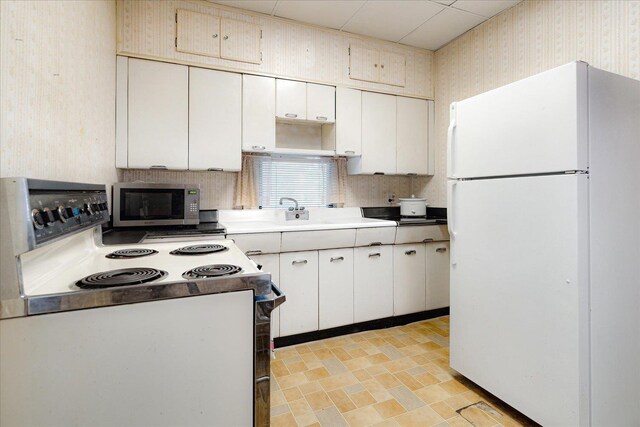2102 Carr Ave, Memphis, TN 38104 - kitchen with freestanding refrigerator, range with electric stovetop, stainless steel microwave, wallpapered walls, and decorative backsplash