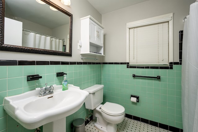 4152 Barfield Rd, Memphis, TN 38117 - bathroom featuring tile walls, a sink, toilet, a wainscoted wall, and tile patterned flooring