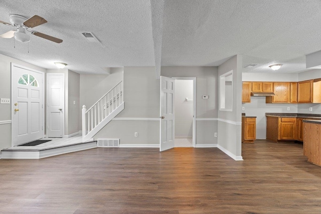 5544 Blossom Ln, Memphis, TN 38115 - unfurnished living room featuring dark wood-style flooring, a ceiling fan, stairway, a textured ceiling, and baseboards