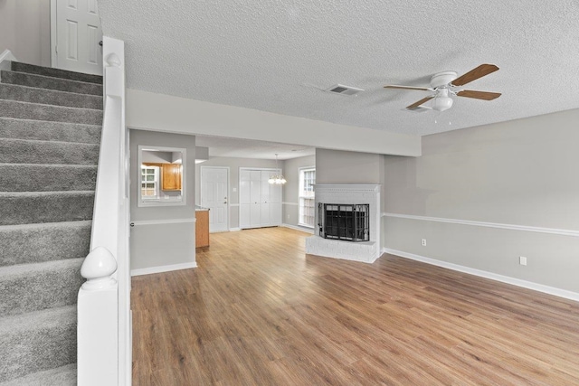 5544 Blossom Ln, Memphis, TN 38115 - unfurnished living room with stairway, ceiling fan, wood finished floors, a textured ceiling, and a fireplace