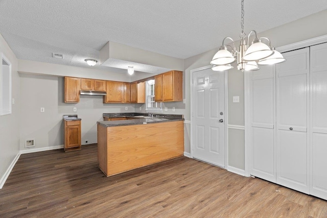 5544 Blossom Ln, Memphis, TN 38115 - kitchen featuring a peninsula, a chandelier, brown cabinets, dark countertops, and dark wood-type flooring
