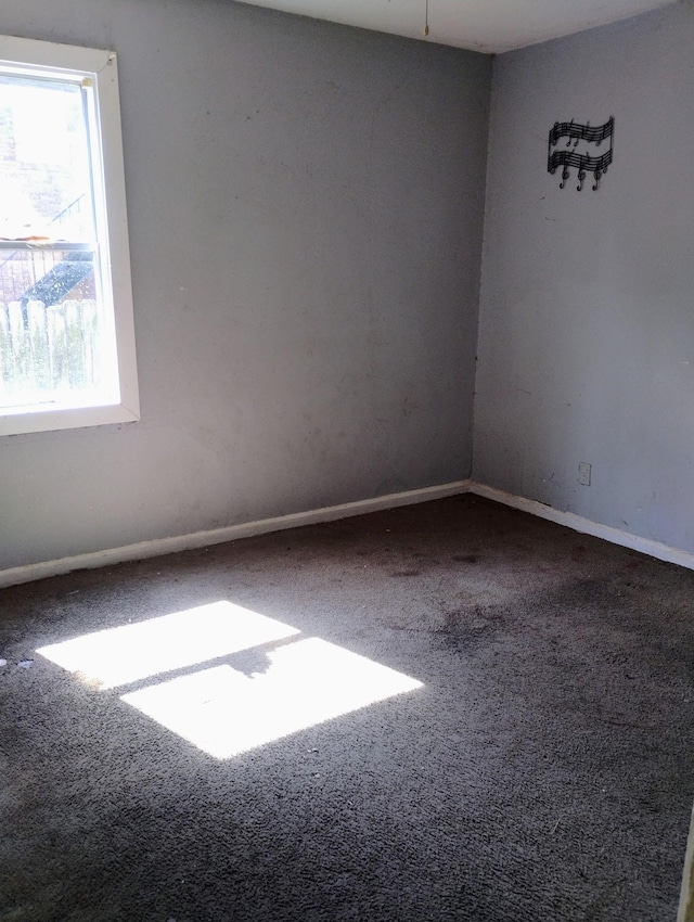 unfurnished room featuring carpet and baseboards