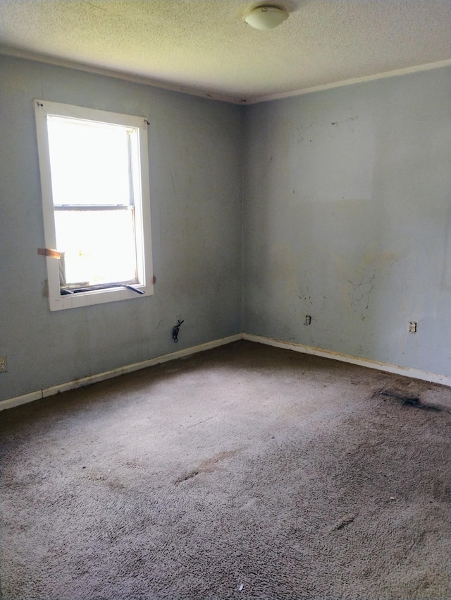 carpeted empty room featuring a textured ceiling and baseboards
