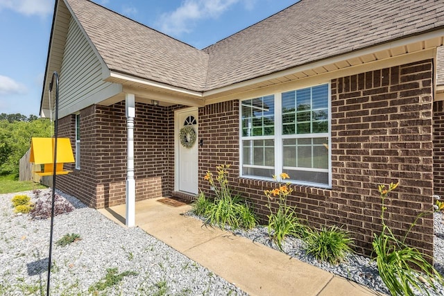 entrance to property with brick siding and roof with shingles