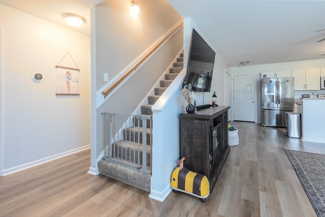 stairway with wood finished floors and baseboards