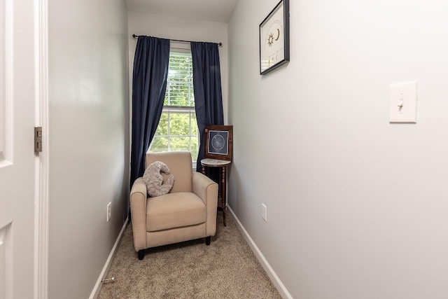 living area featuring light carpet and baseboards