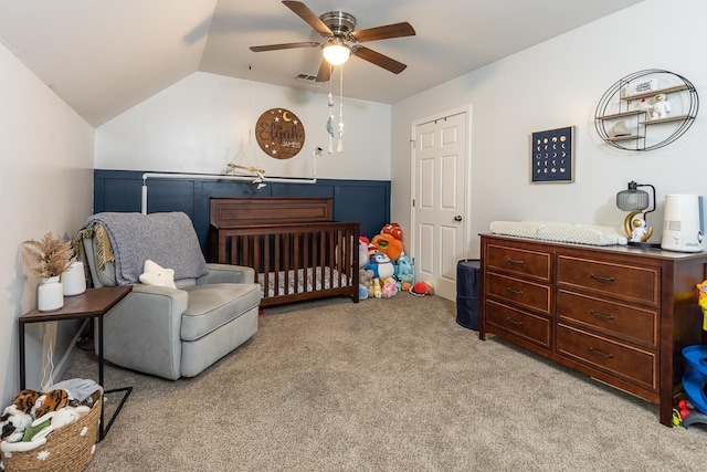 bedroom with light colored carpet, vaulted ceiling, a nursery area, and ceiling fan
