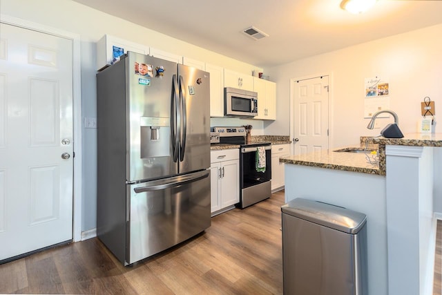 kitchen featuring stainless steel appliances, a sink, dark wood-type flooring, and white cabinetry