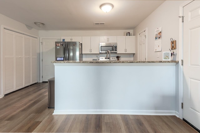 kitchen featuring stainless steel appliances, dark wood-style floors, white cabinetry, and light stone countertops