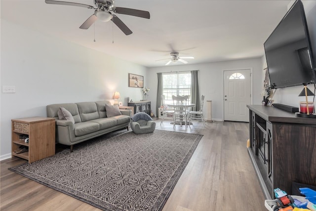 living area featuring a ceiling fan, wood finished floors, and baseboards