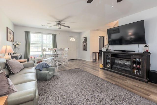 living area featuring a ceiling fan, wood finished floors, and baseboards