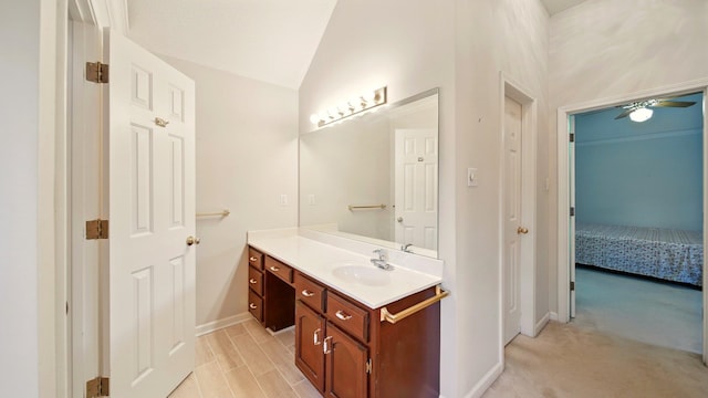 ensuite bathroom with baseboards, vanity, vaulted ceiling, and ceiling fan